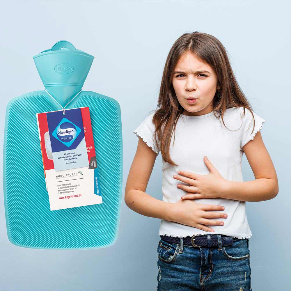 Türkisfarbene Wärmflasche neben Kinderoberkörper, Mädchen mit Hand am Bauch
