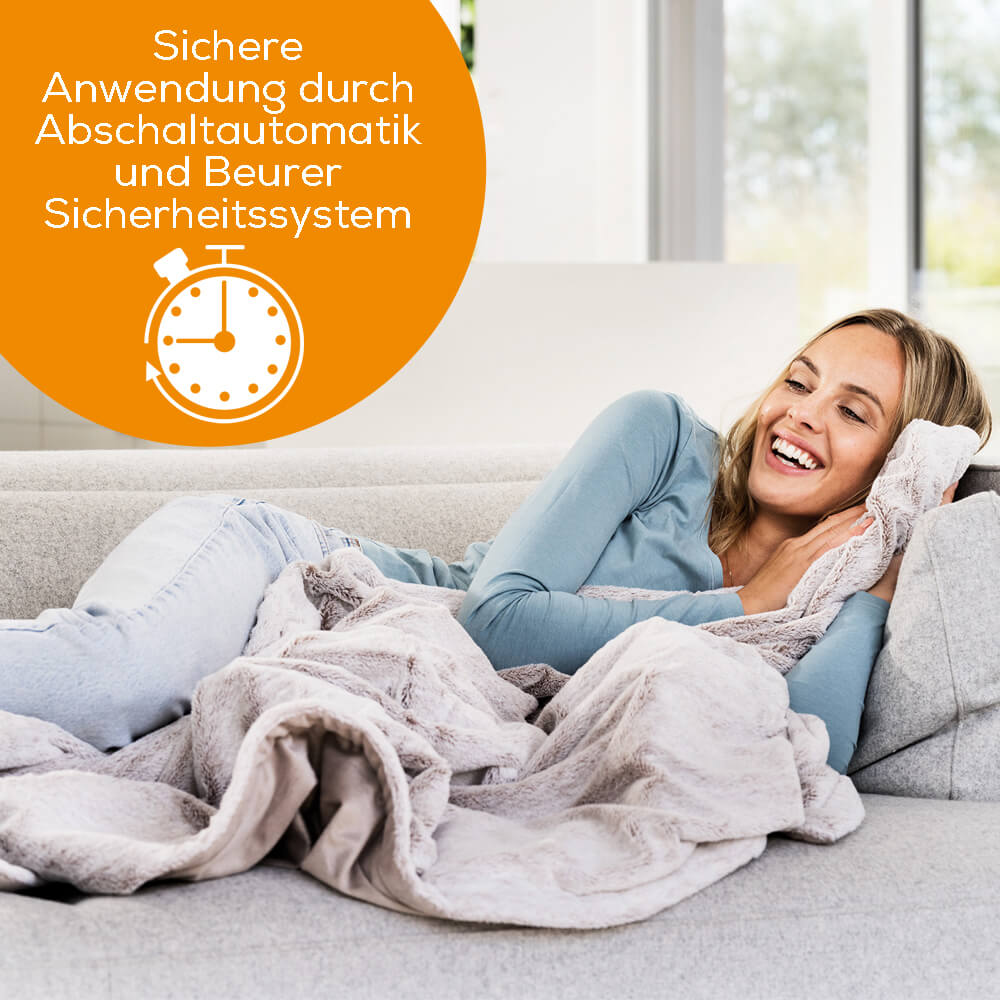 Graue Heizdecke mit ausgebreitetem Fleece auf Sofa, offen liegend